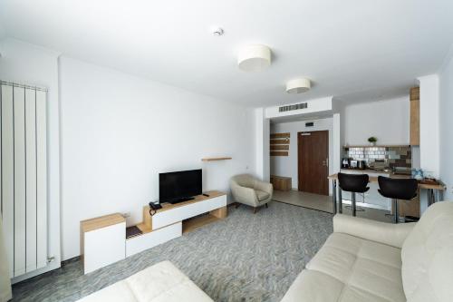 a living room with a white couch and a tv at Hotel Manor in Mamaia Nord