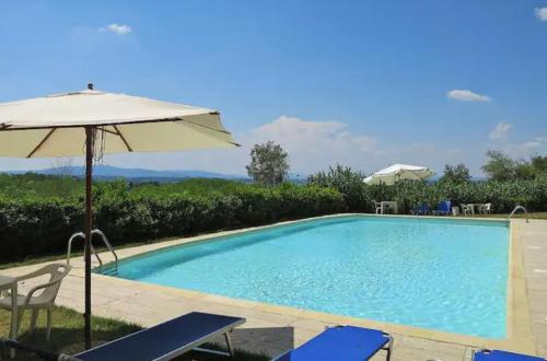 a swimming pool with an umbrella and chairs at Agriturismo La Moraia in Poggibonsi