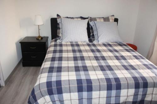 a bed with a blue and white plaid blanket at Chez Lio & Jess in Obernai
