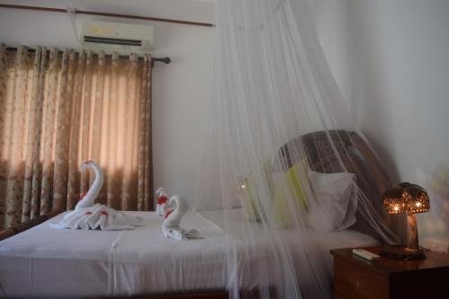 two swans sitting on a bed in a bedroom at Chalet Bamboo Vert in La Digue