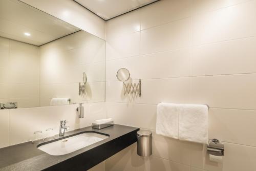W białej łazience znajduje się umywalka i lustro. w obiekcie Fletcher Hotel-Restaurant de Wageningsche Berg w mieście Wageningen