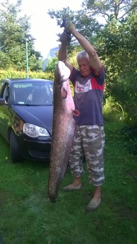 a man holding a large fish in front of a car at Agroturystyka Ruta nad zalewem Siemianówka in Łuka