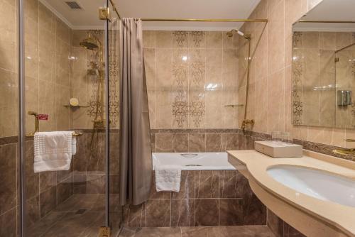 y baño con bañera, lavamanos y ducha. en The Royal Mezbon Hotel & SPA en Tashkent