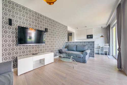 a living room with a couch and a tv on a wall at Apartamenty Sun & Snow Osiedle Pogodne in Kołobrzeg