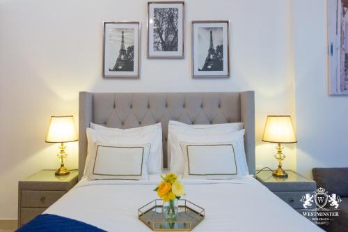 a bedroom with a bed with two lamps and flowers on it at Westminster Claren Tower - Downtown in Dubai