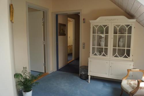 a hallway with a white hutch and a chair at Nilles Kro in Sabro