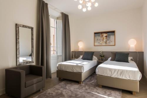 a bedroom with two beds and a chair and a mirror at Apartments Florence - Duomo Contemporary in Florence