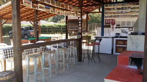 a patio with a bar with stools and a kitchen at POUSADA ESTAÇÃO MARMELO in Queimada