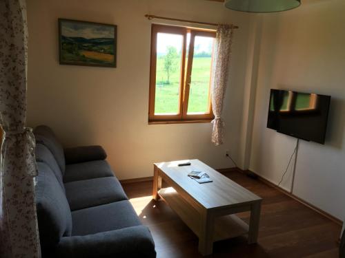 a living room with a couch and a table and a window at Ubytování Ranč Malenice in Malenitz