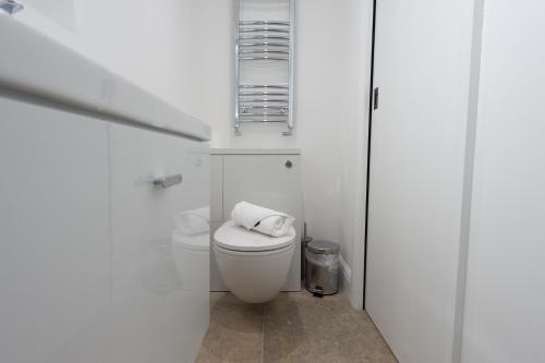 a white bathroom with a toilet and a window at The Withies Inn in Godalming