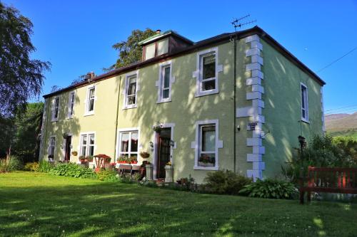 a green and yellow house on a lawn at Inverlochy Villas (Adults Only) in Fort William