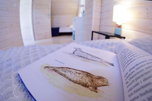 a book with two seashells sitting on a bed at Osada Natura in Śliwin