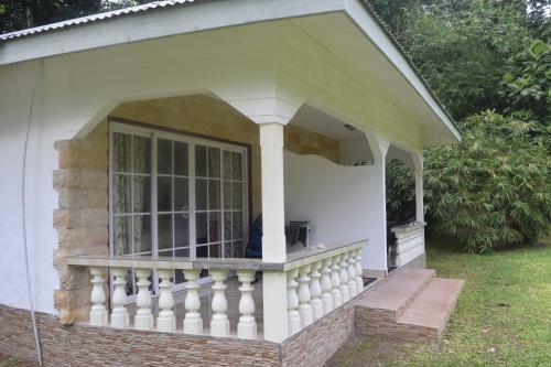 a white house with a porch with a balcony at Chalet Bamboo Vert in La Digue