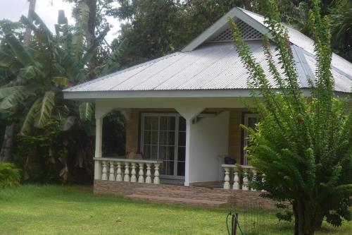 a small house with a white roof and a porch at Chalet Bamboo Vert in La Digue