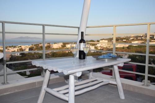 a table with a bottle of wine and glasses on a balcony at Santorini Garden Homes in Mesaria