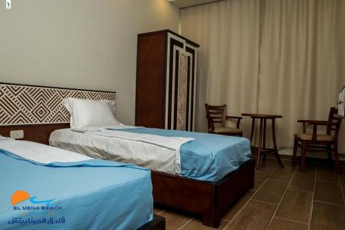 a hotel room with two beds and a table and chairs at El Mena Beach in Ras El Bar