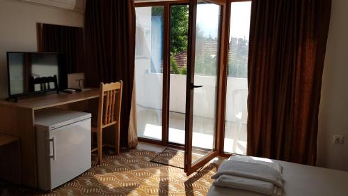 a room with a bed and a desk and a window at Guest House Trakia Primorsko in Primorsko