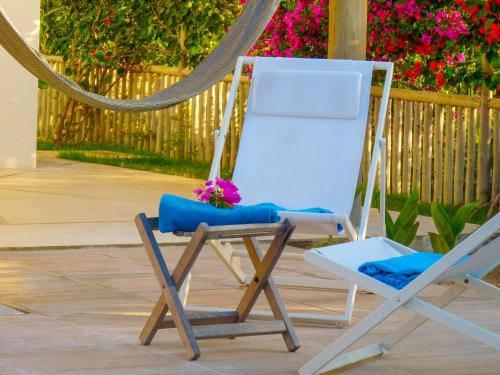 a white rocking chair and a blue chair with flowers at Pousada Recanto Beija-Flor in Fortim