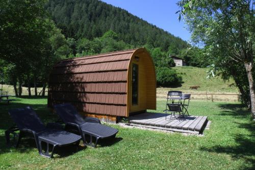 a small wooden cabin with chairs and a table at Presanella Mountain Lodge in Temù