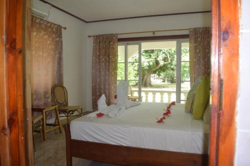 - une chambre avec un lit doté de draps blancs et une fenêtre dans l'établissement Chalet Bamboo Vert, à La Digue