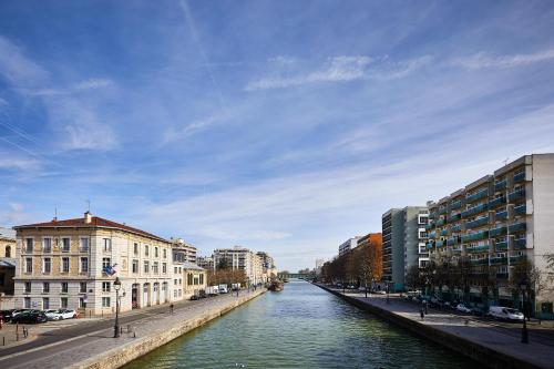 a river in the middle of a city with buildings at St Christopher's Inn Paris - Canal in Paris
