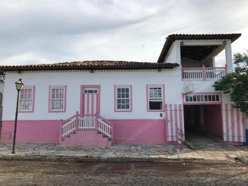 a pink and white house with a porch and stairs at Pousada Casa Matutina in Pirenópolis