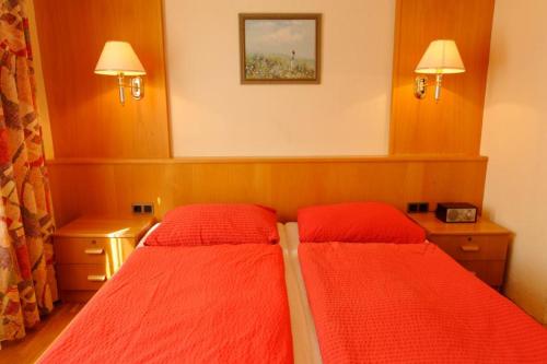 a bedroom with two beds with red sheets at Gasthof Pension „Zur Hammerschmiede“ in Drosendorf Altstadt