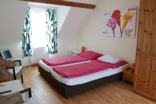 a bedroom with a large bed with red sheets at Gasthof Pension „Zur Hammerschmiede“ in Drosendorf Altstadt