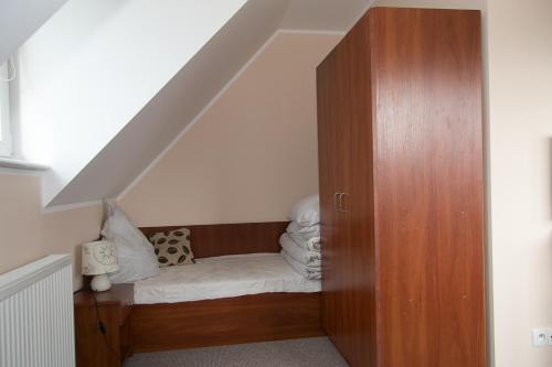 a bed under the stairs with a wooden cabinet at Apartamenty Fala in Rowy