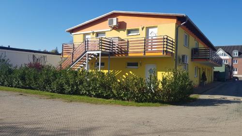 a yellow house with a balcony on the side of it at Appartement Vermietung Brunner in Rostock