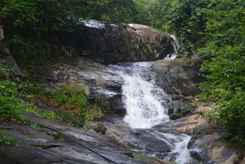 a waterfall on the side of a rocky hill at Stream Garden Mountain Resort in Kalpetta