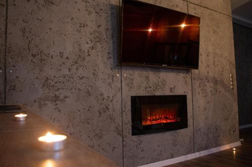 a fireplace in a room with candles on a table at Apartament MINUS in Mrągowo