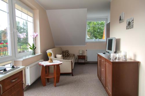 a living room with a television and a desk with a chair at Apartamenty Fala in Rowy