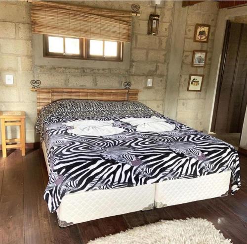 a zebra print bed in a bedroom with a window at Pousada Rota dos Pássaros in São Bento do Sapucaí