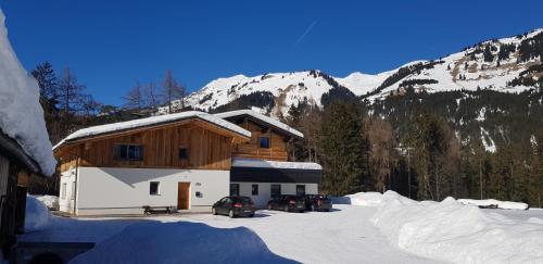 a building in the snow with mountains in the background at Haus Huber in Bach