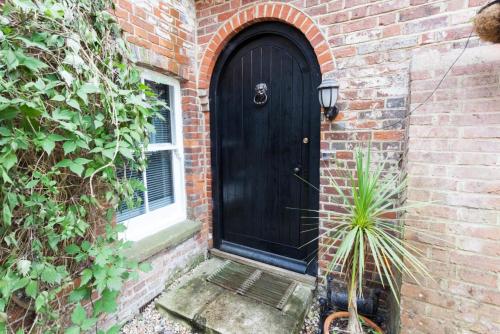 a black door on a brick building with a plant at Hanger Down House Bed and Breakfast in Arundel