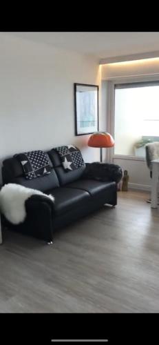 a living room with a black couch and a red lamp at Alte Teestube Appartement 3 Penthouse in Norderney