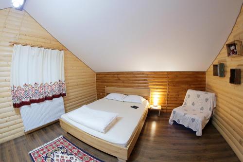 a small bedroom with a bed and a chair at Cabana Todireni Vatra Dornei in Vatra Dornei