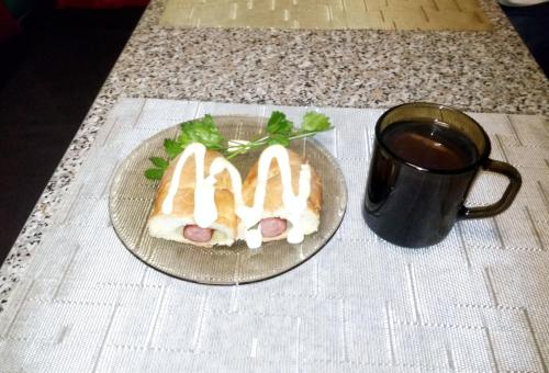 two hot dogs on a plate next to a cup of coffee at Parasolka in Lutsk