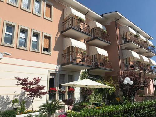 an apartment building with balconies and an umbrella at Hotel Alsazia in Sirmione