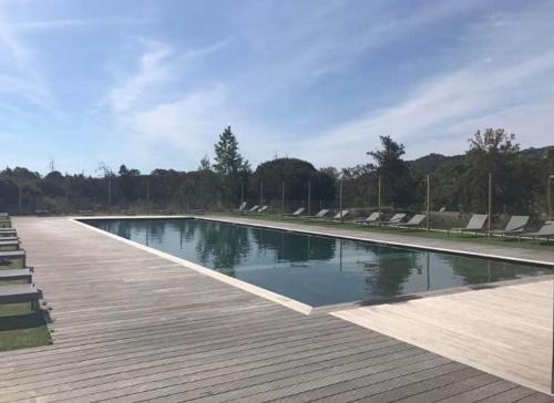 une piscine avec des chaises et une terrasse en bois dans l'établissement Porto-Vecchio Baie Santa Giulia appartement une chambre 4-5 personnes, à Porto-Vecchio