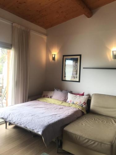 une chambre avec un lit, un canapé et une fenêtre dans l'établissement Porto-Vecchio Baie Santa Giulia appartement une chambre 4-5 personnes, à Porto-Vecchio