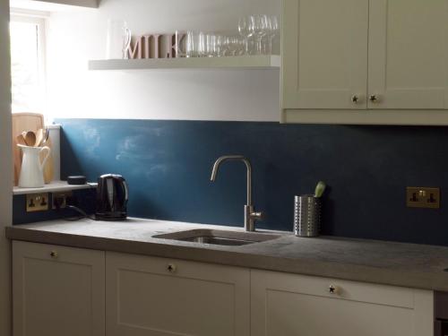 cocina con fregadero y pared azul en Mews Cottage Ardoch Lodge Strathyre, en Strathyre