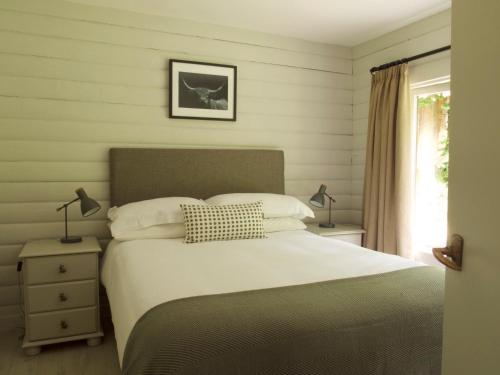 a bedroom with a bed and two lamps and a window at Mews Cottage Ardoch Lodge Strathyre in Strathyre
