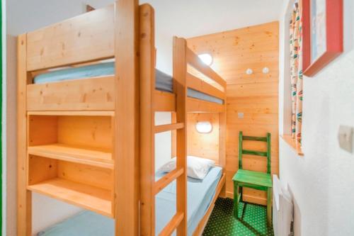 a room with bunk beds and a green chair at Residence Les Sentiers du Tueda - maeva Home in Méribel