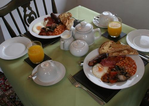 a table with plates of breakfast food and orange juice at Natal House Bed & Breakfast in Polperro