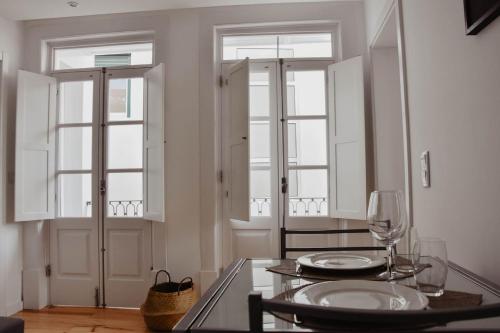 een eetkamer met een tafel en twee ramen bij Apartamento acolhedor e elegante em prédio típico - Self check in in Coimbra
