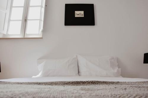 a bedroom with white walls and a bed with white pillows at Apartamento acolhedor e elegante em prédio típico - Self check in in Coimbra