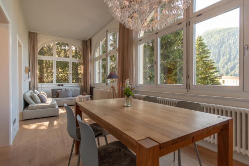 uma sala de jantar com mesa, cadeiras e janelas em Hotel Edelweiss em Davos