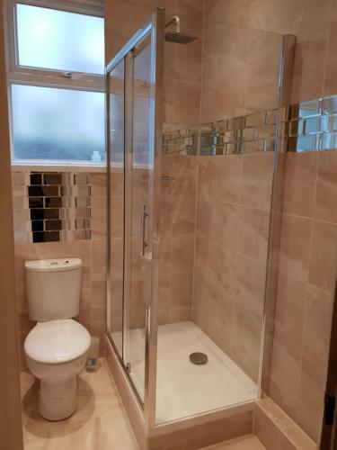 uma casa de banho com um chuveiro, um WC e uma janela. em luxury two bedroom apartment in Thornton heath em Thornton Heath